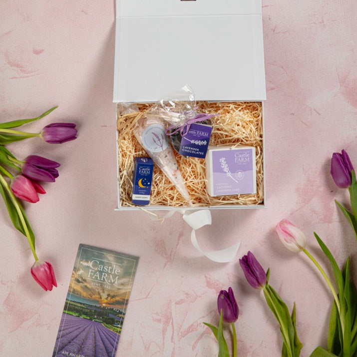 Gift box with lavender items on a pink textured surface with tulips.